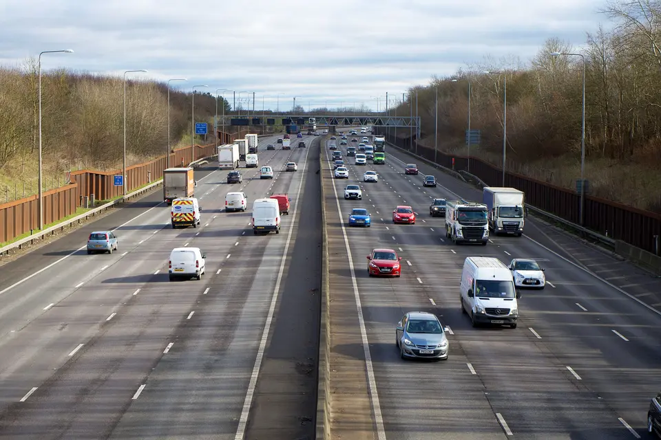 Cars, vans and lorries on a busy six-lane UK motorway on a clear day.