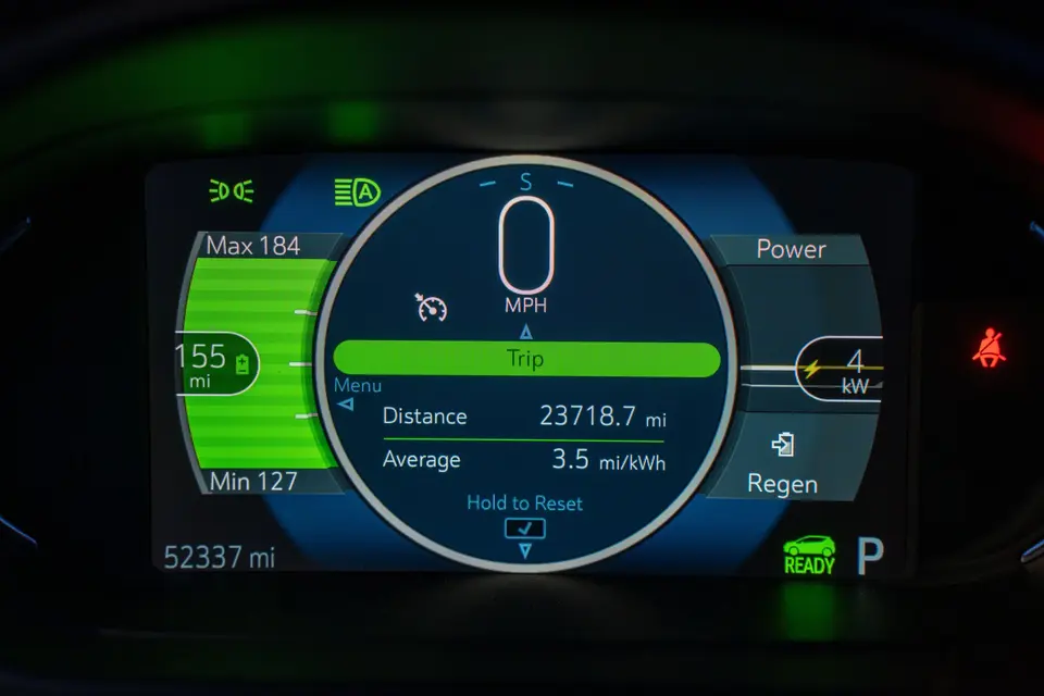 The instrument panel of an electric car shows a range of 155 miles and 52,337 miles on the odometer.